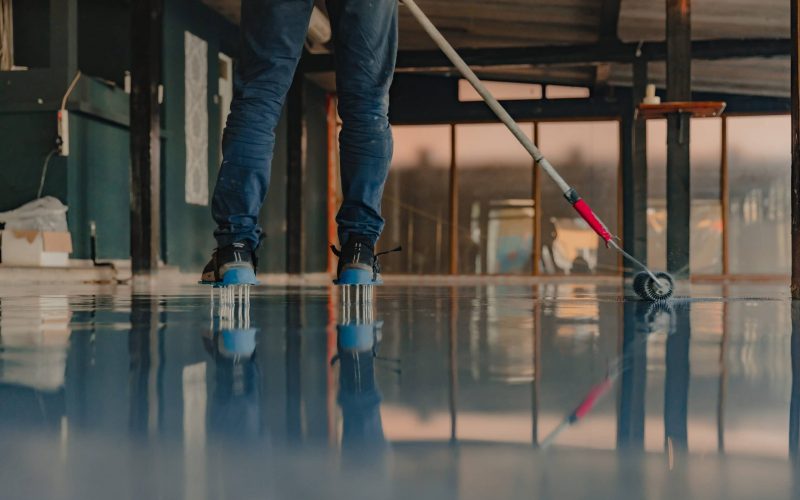 The worker applies gray epoxy resin to the new floor