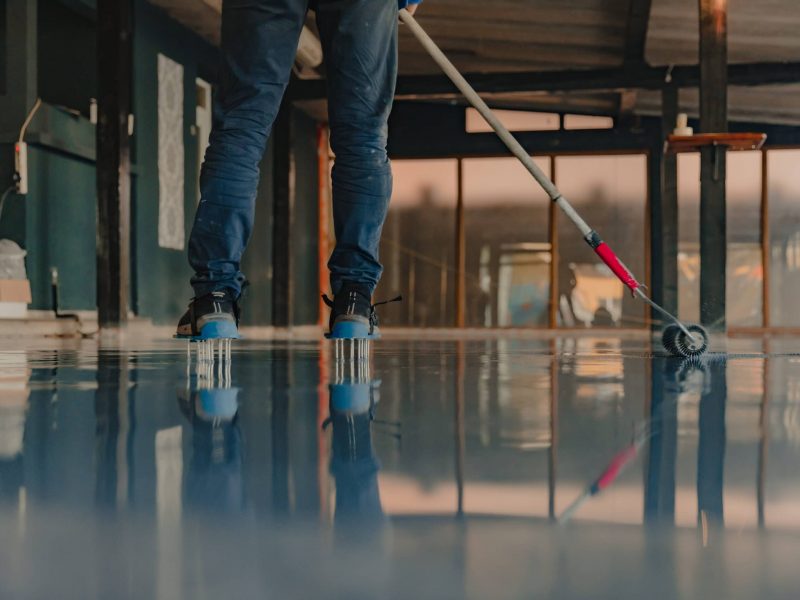 The worker applies gray epoxy resin to the new floor