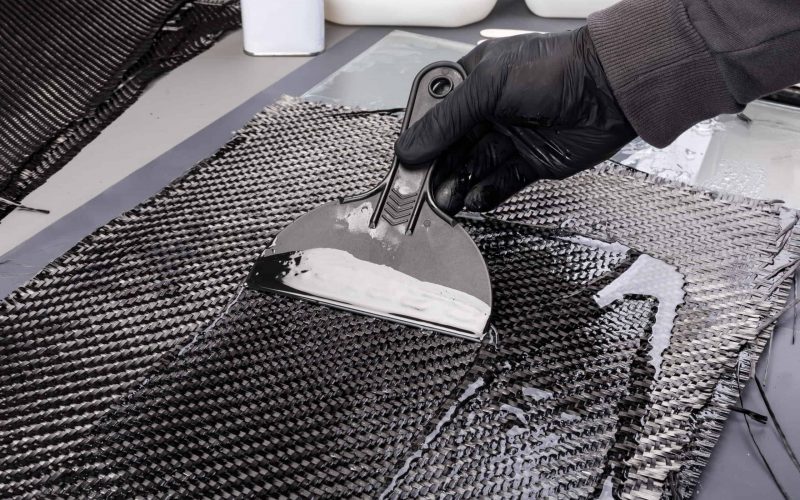 Rolls with various real woven carbon fiber enforcement raw material cloth. composite material automotive and car tuning industry high tech background.