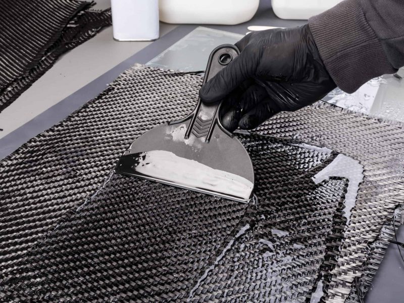 Rolls with various real woven carbon fiber enforcement raw material cloth. composite material automotive and car tuning industry high tech background.